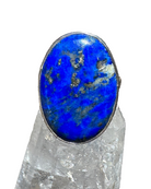 Ring with a blue stone on a clear crystal stand against a blurred background